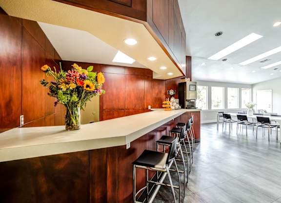 A kitchen with a long counter and bar stools.