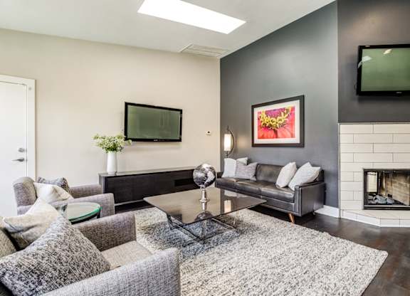 A modern living room with a grey couch, a coffee table, and a fireplace.