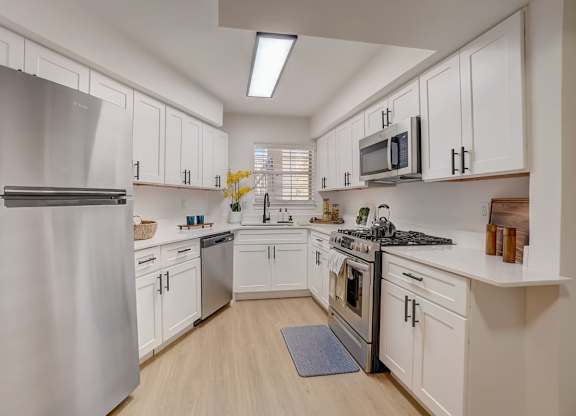 A modern kitchen with white cabinets and stainless steel appliances.