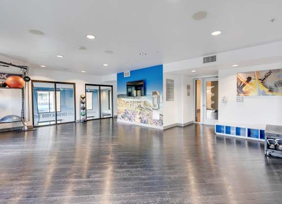 A spacious room with a wooden floor and a blue wall with a mural.