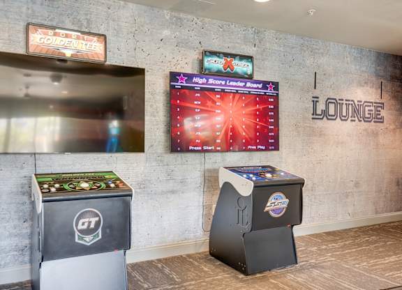 A lounge area with a high score leaderboard and two arcade machines.