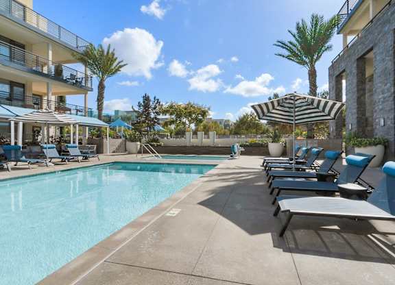 A pool area with sun loungers and a striped umbrella.