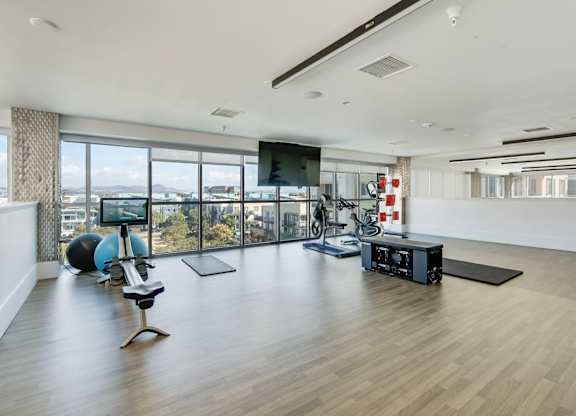 A spacious room with a wooden floor, a television, and exercise equipment.