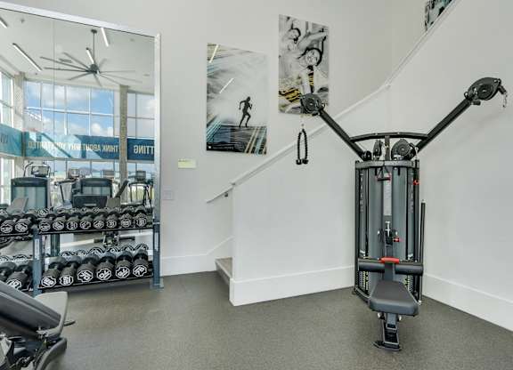 A gym with a weightlifting machine in the foreground.