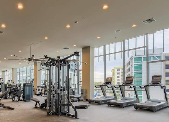 A gym with a variety of equipment including treadmills, weights, and exercise machines.