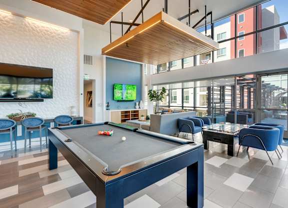 A pool table is in the middle of a room with blue chairs.