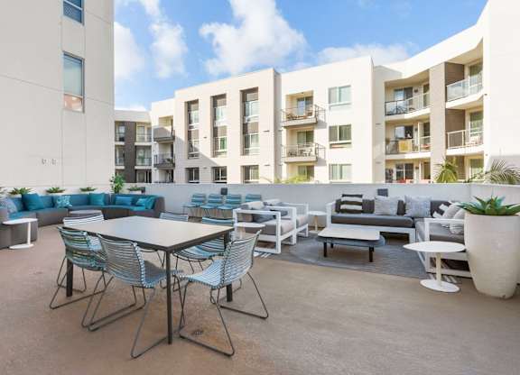 A patio with a table and chairs is surrounded by apartment buildings.