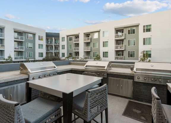 A patio with a table and chairs overlooking apartment buildings.