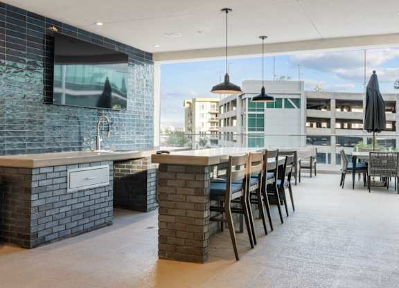 A modern bar area with a television and a view of the city.