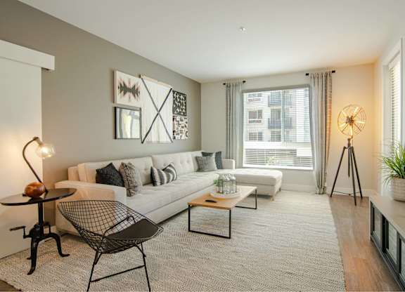 A living room with a white couch, a black chair, and a small table with a plant on it.