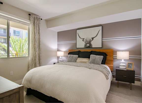 A bedroom with a large bed and a painting above it.