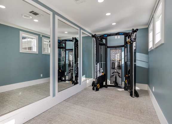 A spacious home gym with a mirrored wall and a treadmill.