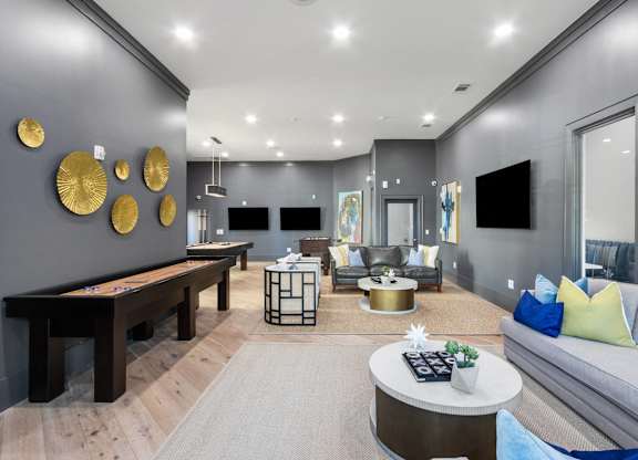 A modern living room with a pool table and a grey sofa.