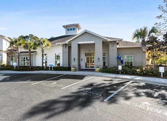 A white building with a flag on the right side and a parking lot in front.