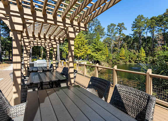 A wooden deck with a table and chairs overlooking a forest.