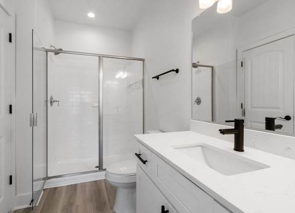 A white bathroom with a toilet, sink, and shower.