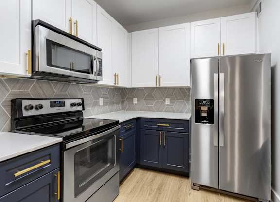 Apartments in Charleston, SC, with In-Unit Washer and Dryer - The Avenues at Verdier Pointe - Kitchen with Wood-Style Flooring, Two-Tone Cabinetry, Range, French Door Refrigerator, and Mounted Microwave.