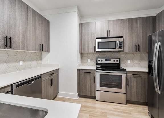 A modern kitchen with a stainless steel refrigerator and a white countertop.