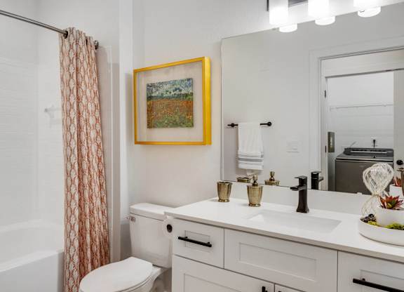 A bathroom with a white toilet, sink, and a painting hanging on the wall.