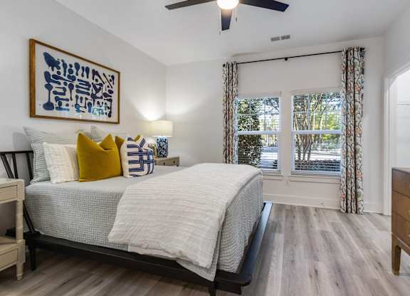 A bedroom with a bed, dresser, and a ceiling fan.