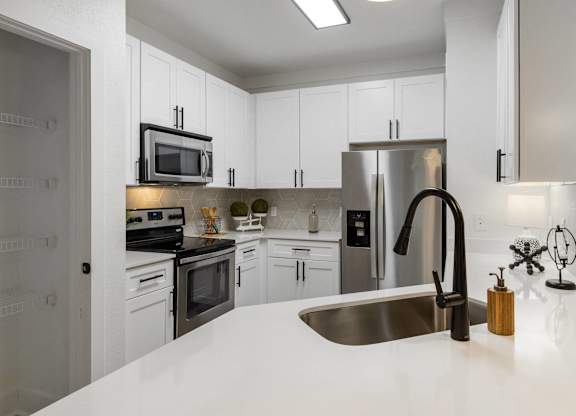 A modern kitchen with white cabinets and stainless steel appliances.