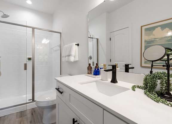 A white bathroom with a glass shower door and a white toilet.