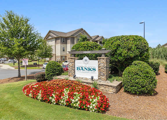 A sign for Banks in front of a building with a flower bed in the foreground.