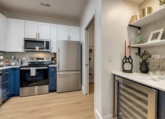 A kitchen with a refrigerator, oven, and microwave.