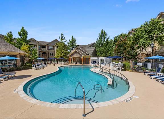 A large outdoor swimming pool surrounded by lounge chairs and umbrellas.