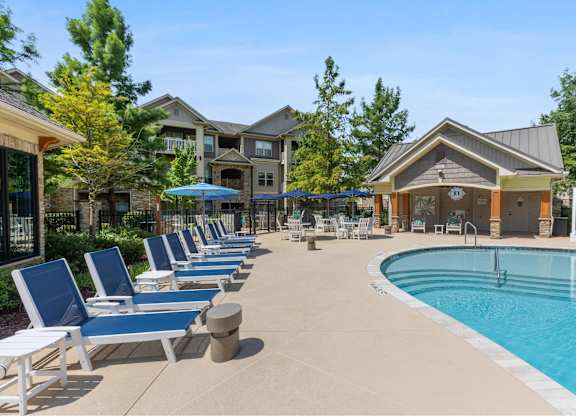 A pool area with lounge chairs and a building in the background.