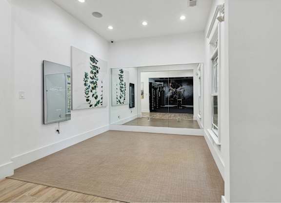 A hallway with a carpeted floor and a mirror on the wall.