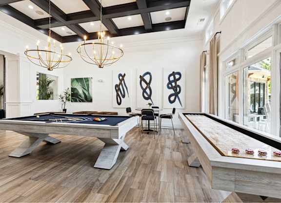 A pool table is in the middle of a room with a wooden floor and a black ceiling.