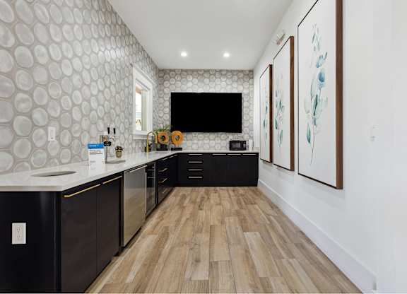 A modern kitchen with a wooden floor and black cabinets.