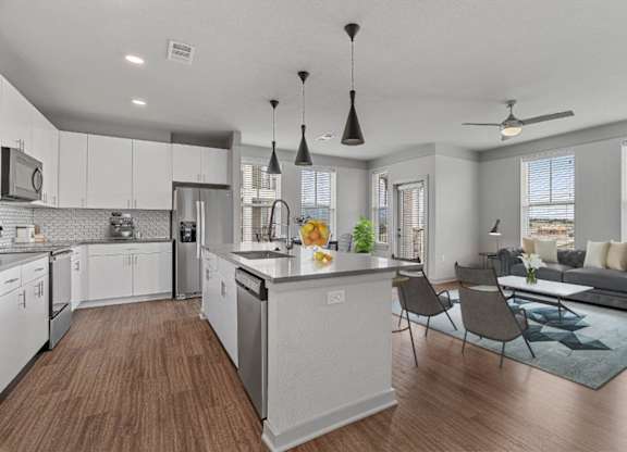 A modern kitchen with white cabinets and a wooden floor.