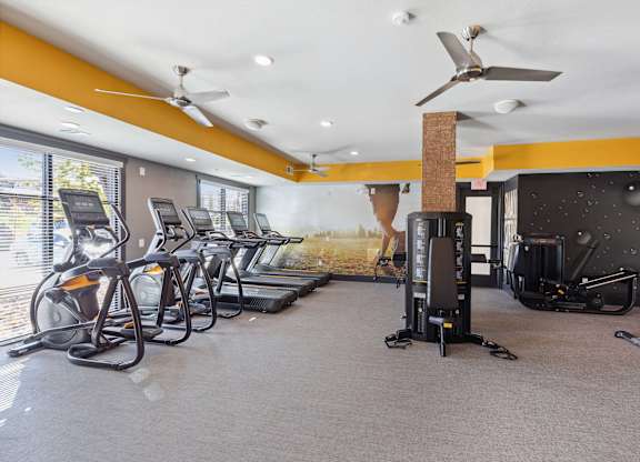 A gym with treadmills, exercise bikes, and a fan.