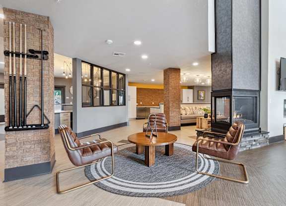 A modern living room with a fireplace and leather chairs.