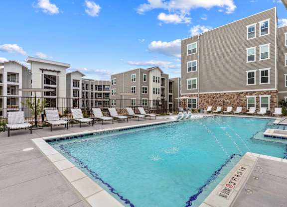 A swimming pool surrounded by lounge chairs and buildings.