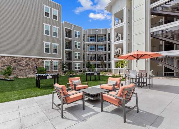 A patio with a table and chairs is in front of a building.