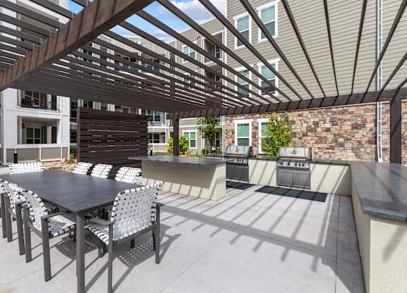 A patio with a table and chairs under a wooden pergola.