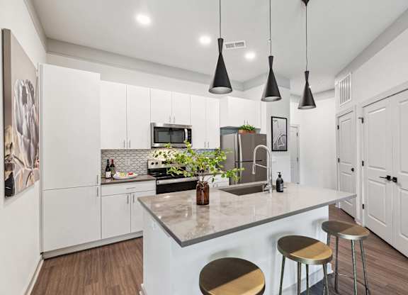 A kitchen with a white counter and bar stools.