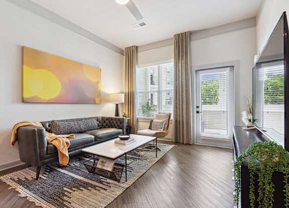 A modern living room with a grey sofa and a large abstract painting on the wall.
