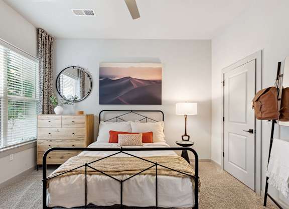 A bedroom with a bed, a dresser, a mirror, a lamp, and a painting on the wall.