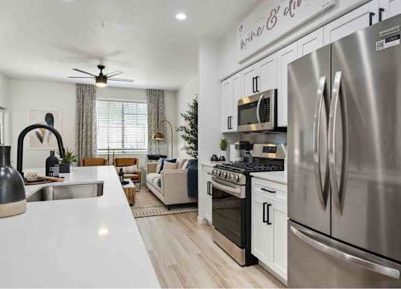 A modern kitchen with a stainless steel refrigerator and a dining area with a couch and chairs.