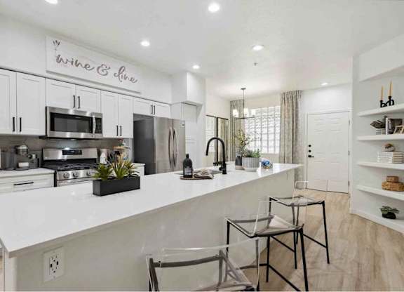 A modern kitchen with a white countertop and stainless steel appliances.