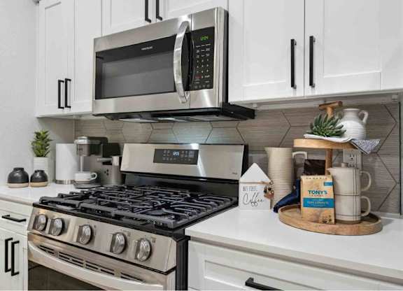 A modern kitchen with a stainless steel stove and a microwave above it.