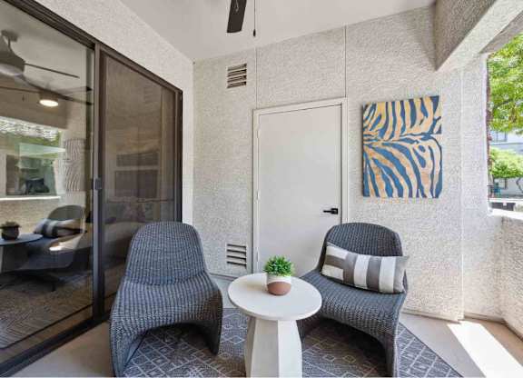 A living room with a grey chair, a white table, and a painting on the wall.