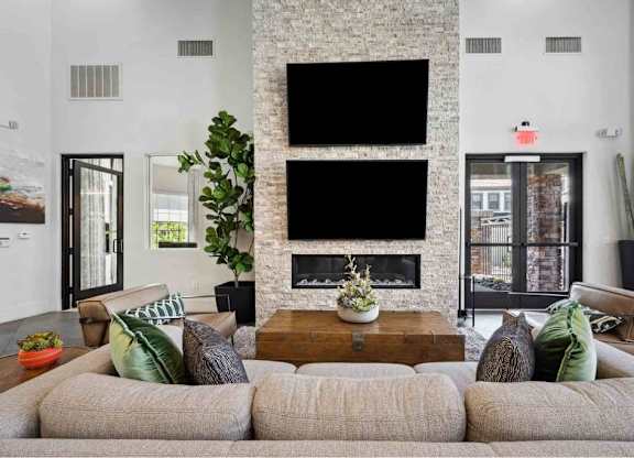 A living room with a grey sofa and a fireplace.