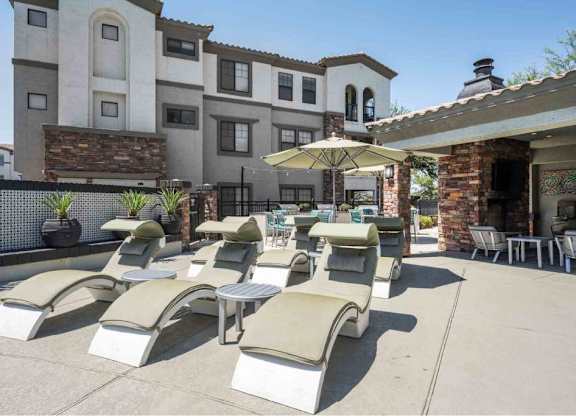 A row of sun loungers are arranged on a patio in front of a building.