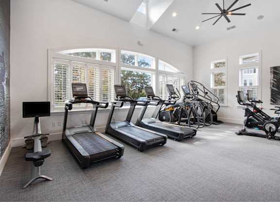 the gym has plenty of cardio equipment and windows