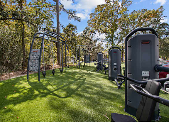 a group of exercise equipment on the grass at a park